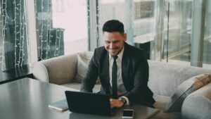 Man in suit smiling while using a laptop