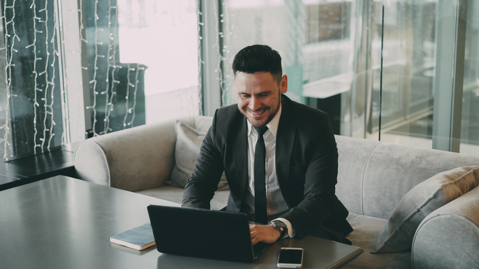Man in suit smiling while using a laptop