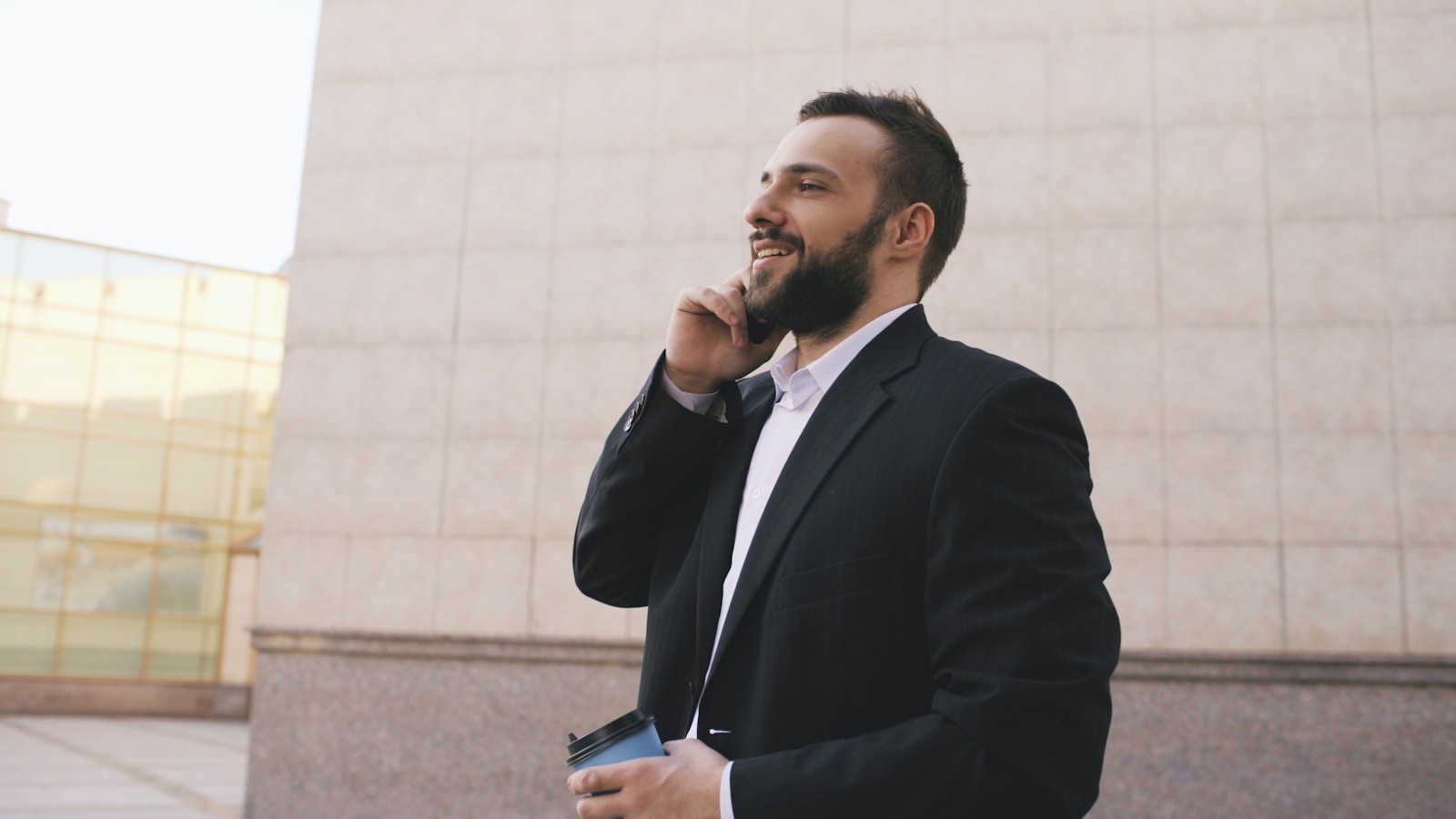 Man in suit talking on phone holding coffee cup