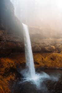 A tall waterfall cascades down a rocky cliff face.