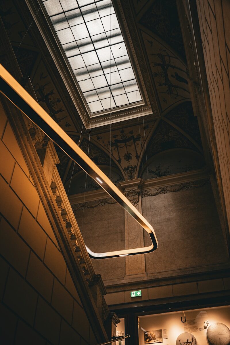 Modern lamp illuminates ornate ceiling and skylight
