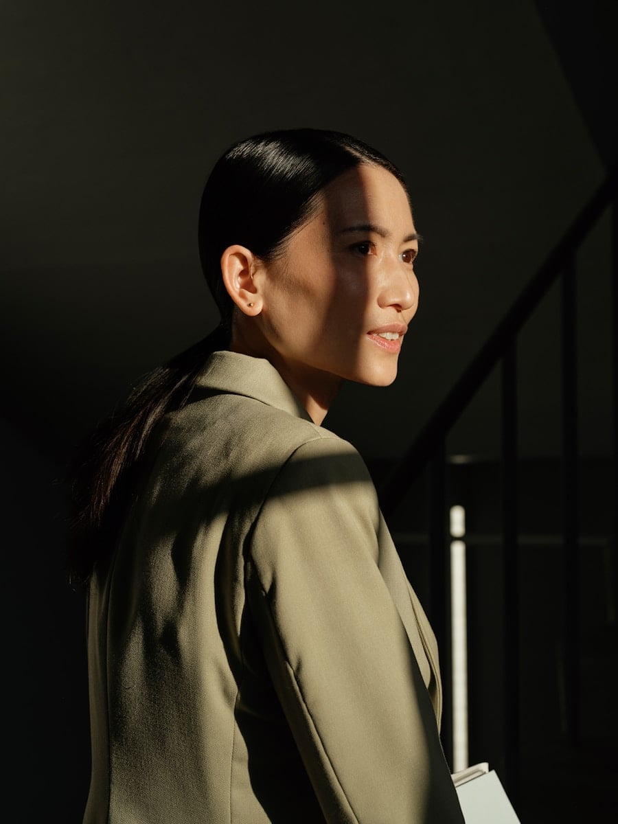 Woman in a blazer with sunlight on her face.