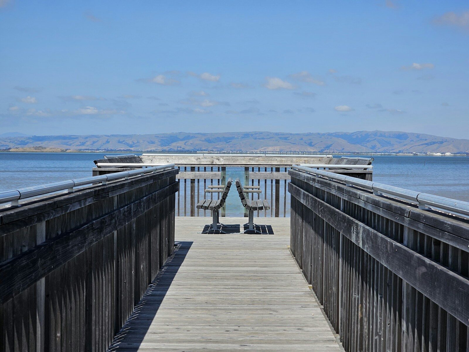 a wooden pier with a bench on the end of it