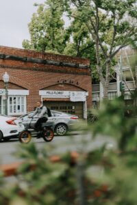 A person rides a bike past a brick building.