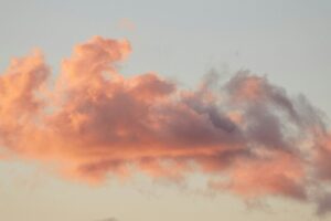 Pink and orange clouds against a pale sky at sunset.