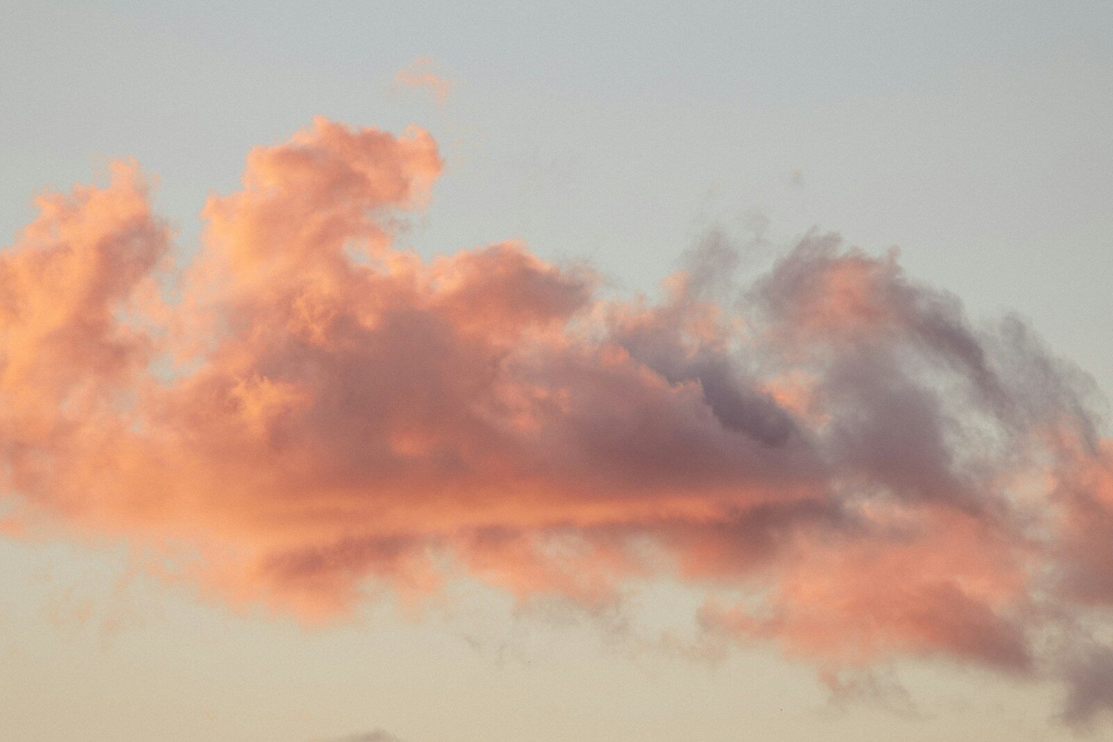 Pink and orange clouds against a pale sky at sunset.