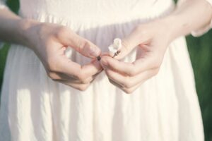 Woman's hands holding a small white flower