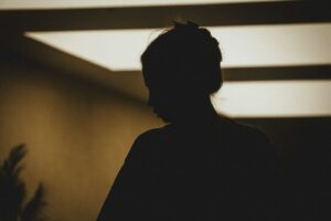 A person in silhouette against a warm light with hair in a bun