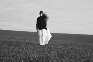Woman in flowing dress walking in a grassy field